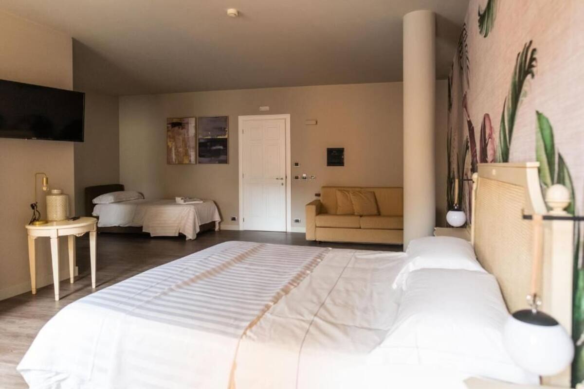 Une chambre d’hôtel avec un grand lit, un canapé, une télévision et un mur orné d’une fresque florale.