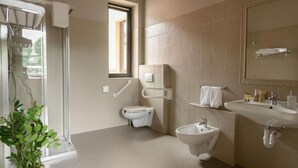 Un baño moderno con inodoro, bidé, lavamanos y ventana que proporciona luz natural.