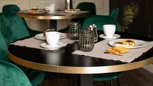 Un comedor con mesas redondas, sillas tapizadas en verde y un mural en la pared.