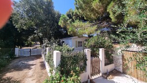 A rustic house surrounded by a wooden fence, with a dirt path leading to the entrance. - Quiet chalet under the trees 3 km from Bonifacio and 2 km from the beaches (Bonifacio)