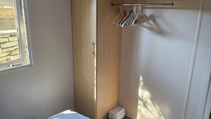 A bedroom with a bed, a wardrobe, and a small window. - Quiet chalet under the trees 3 km from Bonifacio and 2 km from the beaches (Bonifacio)