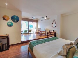 Habitación de hotel con cama, escritorio, silla, una mesita, espejo y vistas al exterior.