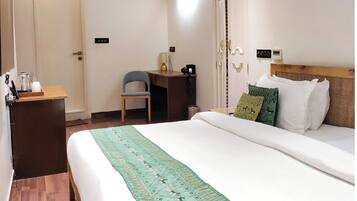 Habitación de hotel con cama, escritorio, silla y equipo de aire acondicionado.
