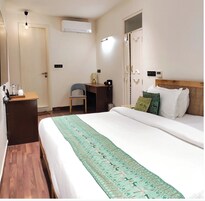 Habitación de hotel con cama, escritorio, silla y equipo de aire acondicionado.