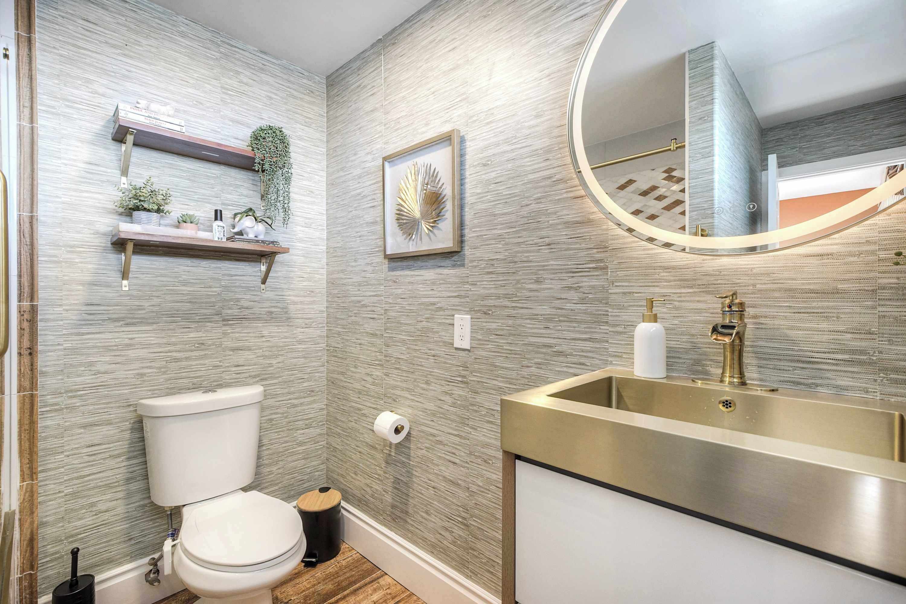 Un baño moderno con inodoro, lavamanos y estantes decorativos.