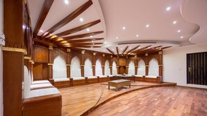 Une pièce spacieuse dotée d’un plancher en bois incurvé, d’un espace de détente central avec des bancs rembourrés et d’un plafond haut avec des poutres en bois et un éclairage encastré.