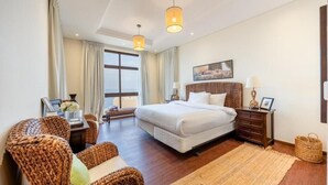 Une chambre spacieuse avec un grand lit, des meubles en osier et une vue sur la ville.