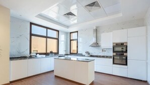Une cuisine moderne dotée d’un îlot central, de meubles blancs et d’une grande fenêtre qui laisse entrer la lumière naturelle.