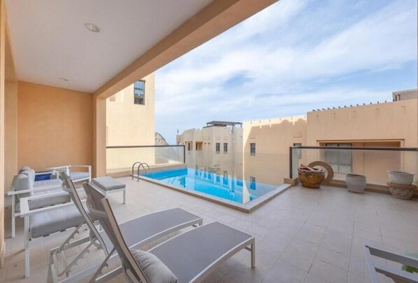 A rooftop pool area with lounge chairs and a glass balustrade. - Bloomfields Stunning 4BR Villa Fujairah (Dibba)