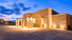 A modern building with stone walls and a flat roof, featuring a spacious outdoor area with a seating arrangement. - Vista Mare Gold Villa Heated Pool (Dramia)