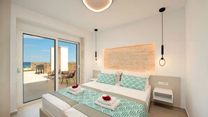 A modern bedroom with a large bed, a view of the sea through a sliding door, a small table with chairs, and a simple nightstand. - Vista Mare Gold Villa Heated Pool (Dramia)