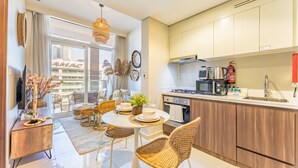 Une cuisine moderne avec des meubles en bois, une cuisinière à gaz et un four à micro-ondes. On y trouve un coin repas avec des chaises en osier et une table ronde.