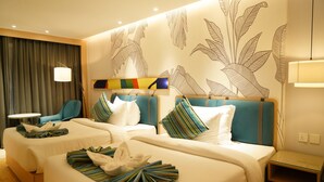 A hotel room with two beds, a desk, a chair, and a wall with a leaf pattern.