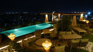 A rooftop pool area with lounge chairs, tables, and ambient lighting. - Clarion Inn Greywall By Choice Hotels (Amritsar)