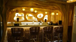 A bar area with wooden chairs, a counter, and pendant lighting. - Clarion Inn Greywall By Choice Hotels (Amritsar)