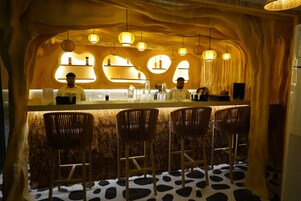 Una zona de bar con sillas de madera, una barra y lámparas colgantes.