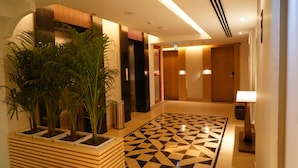 A hotel lobby with a geometric patterned floor, a reception desk, and potted plants. - Clarion Inn Greywall By Choice Hotels (Amritsar)