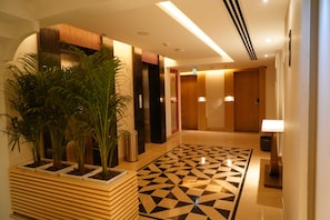 Rebedor d'hotel amb un paviment de disseny geomètric, una recepció i plantes en testos.