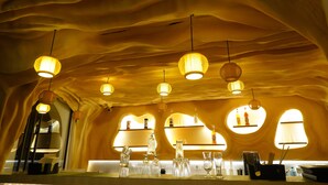 A room with a unique wavy ceiling design, pendant lighting, and a bar area with shelves and glassware. - Clarion Inn Greywall By Choice Hotels (Amritsar)