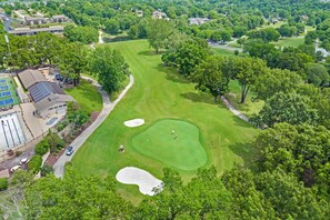 An aerial view of a golf course with a swimming pool, tennis courts, and a building with a sloped roof. - Walk-In 2BR | Golf View | No Stairs | Pools (Branson)