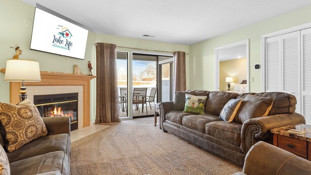 Uma sala de estar com lareira, sofá, poltronas e uma televisão exibindo 'Lake Life Vacation Rentals'.