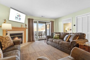 Un salon avec une cheminée, un canapé, un divan et un téléviseur diffusant des images de « Lake Life Vacation Rentals ».