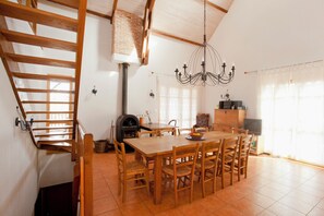 Un coin repas avec une table et des chaises en bois, un lustre et une cheminée en briques.