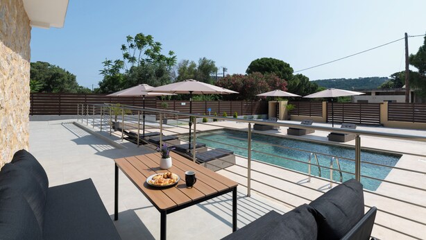 A rooftop pool area with outdoor seating, umbrellas, and a view of the surrounding landscape. - Anthi Luxury Residence- Jasmine (Ialisos)
