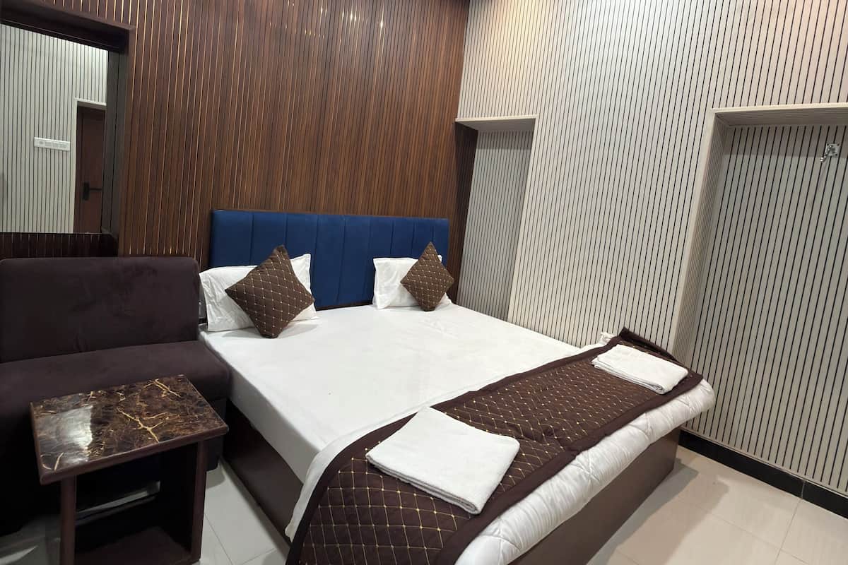Un dormitorio moderno con una cama grande, un sofá, una mesita y un ventilador de techo.