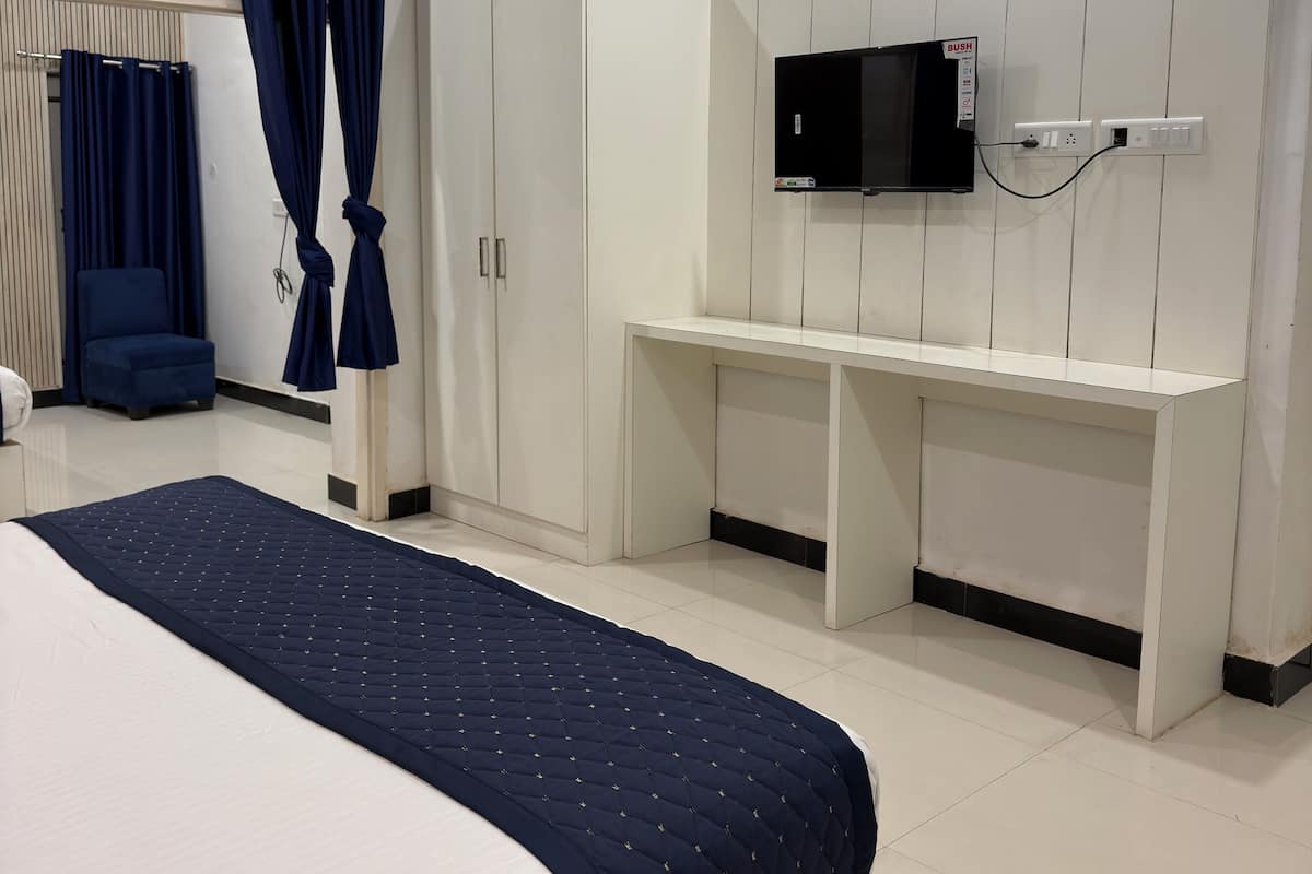 Un dormitorio con cama, escritorio y televisión.