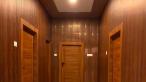 A hallway with wooden doors and a ceiling fan. - Gulmohar Stays (siddhagiribagh)