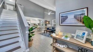 Ein modernes Interieur mit Treppe, Essbereich und Wohnzimmer mit großem Fenster.