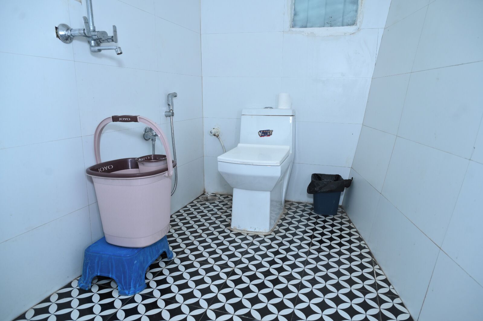 Un baño con inodoro, bidé, cubo de basura y piso estampado.