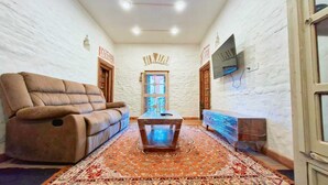 A living room with a sofa, a coffee table, a TV, and a patterned rug. - Tatsaaraa Kavan (Ramgarh)