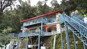 A multi-story building with a red roof, blue railings, and a staircase leading to the upper levels. - Tatsaaraa Kavan (Ramgarh)