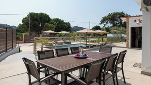 Un patio exterior con piscina, sombrillas y una mesa con sillas.