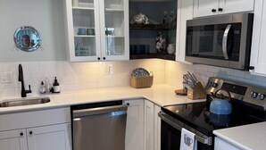 Een moderne keuken met witte kasten, een roestvrijstalen vaatwasser, een zwarte kookplaat en een magnetron.