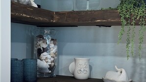 Een keuken met een houten plank, twee wijnglazen, een decoratieve kruik, een mand en een hangende plant.