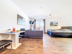 A modern room with a desk, a bed, and a sofa. There are two windows with curtains, a flat-screen TV, and a framed picture on the wall. - Beautiful apartment for 3 people with WIFI, TV, balcony, pets allowed and panoramic view (Klausmen)