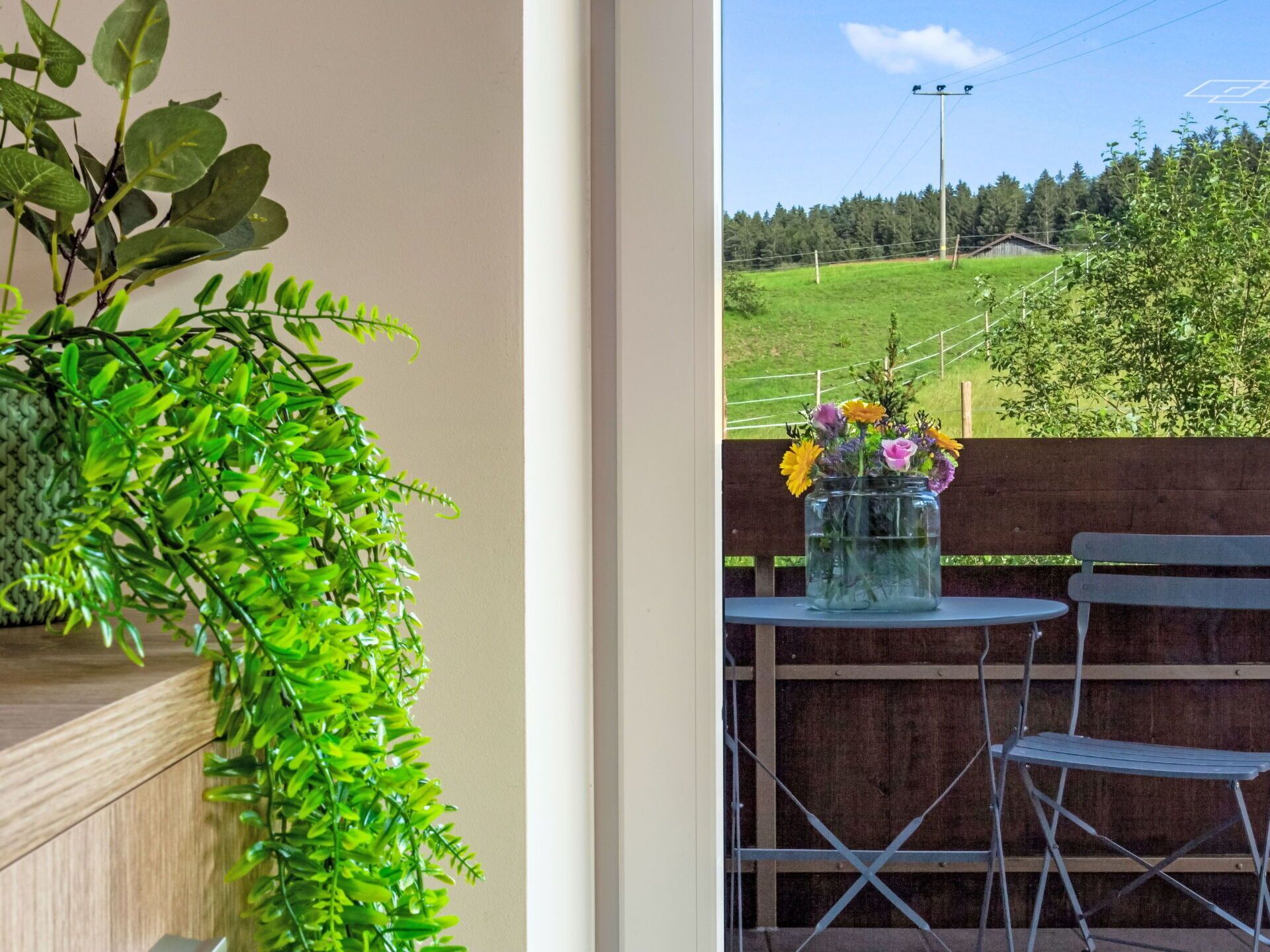 A balcony with a potted plant and a vase of flowers.
