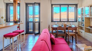 Un ambiente compatto con angolo cottura, zona pranzo e divano.