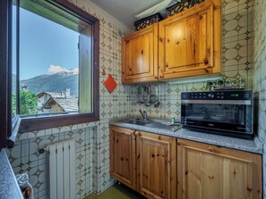 Eine Küche mit Holzausstattung, einem eingebauten Backofen und einem Fenster mit Blick auf einen Berg.