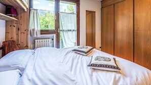 Un dormitori amb un llit, un armari de fusta i una finestra amb cortines.