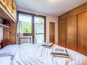 Ein Schlafzimmer mit einem Bett, einem Holzschrank und einem Fenster mit Vorhängen.