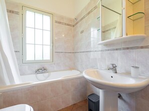 A bathroom with a bathtub, a sink, a window with a curtain, and a mirror. - Beautiful private villa for 5 people with A/C, TV, pets allowed and panoramic view (Villasimius)