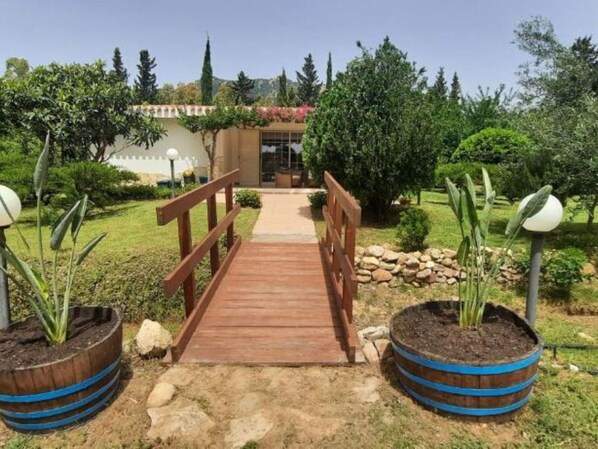 A wooden pathway leading to a building with a white facade and a red flower box. - Beautiful private villa for 5 people with A/C, TV, pets allowed and panoramic view (Villasimius)