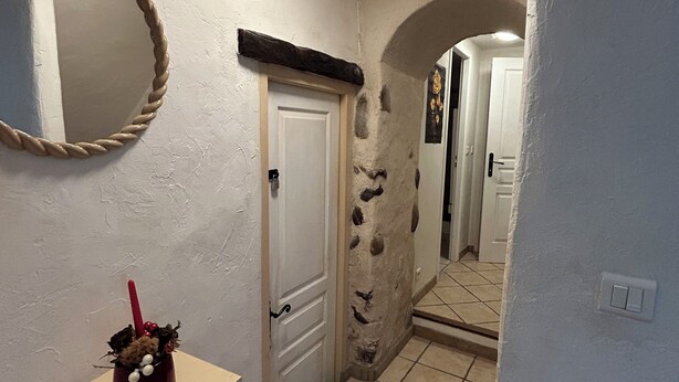 A hallway with a white door, a mirror, and a small table with a candle. - 250m from the Sisteron lake! Fully equipped apartment with office area. (Sisteron)
