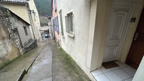 A narrow alleyway between buildings with a door at the end. - 250m from the Sisteron lake! Fully equipped apartment with office area. (Sisteron)
