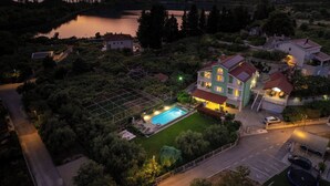 Ein großes Haus mit Swimmingpool, umgeben von Bäumen und einem See.