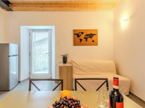Una cocina con refrigerador, una mesa de comedor con frutero, una botella de vino y un mapa del mundo en la pared.